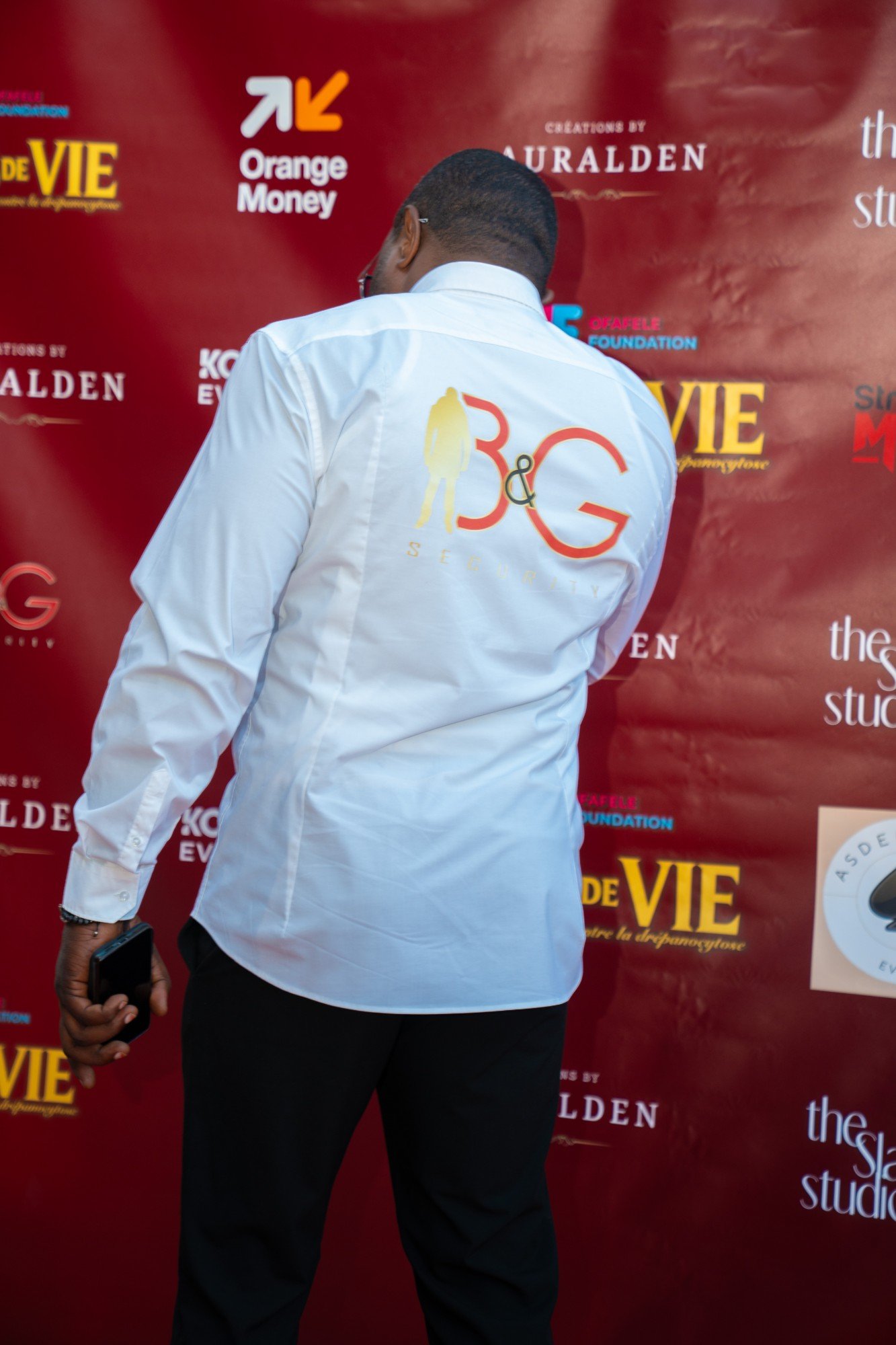 Dos d’une chemise blanche portant le logo B&G SECURITY, lors d’un événement.